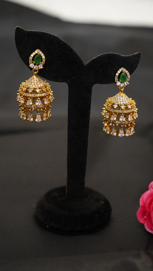 Jhumka earrings with an elegant gold finish, highlighted by green and white stone